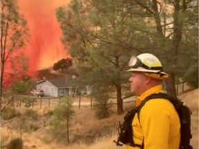 A firefighter is seen as fire retardant is dropped on a lightning complex fire in Berryessa Estates, along Wagon Wheel road, in California, U.S., August 21, 2020 in this still image obtained from a social media video.