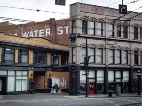 A woman paints a mural on the boarded up windows of a closed Gastown business in downtown Vancouver, on Sunday, April 19, 2020.