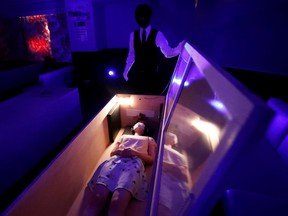 A participant lies inside a mock coffin with plastic shields to maintain social distancing during a coffin horror show, performed by Kowagarasetai (Scare Squad), in Tokyo, Japan August 22, 2020.