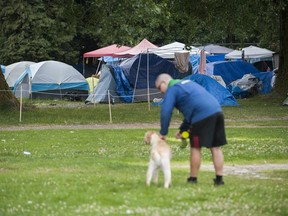 A man walks his dog near a homeless encampment in East Vancouver’s Strathcona Park in late July.