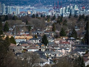 A condo building is seen under construction surrounded by houses as condo towers are seen in the distance in Vancouver, B.C., on Friday March 30, 2018.