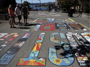 People look at the More Justice More Peace Mural created by 17 artists on display to raise awareness of injustices suffered by Black and Indigenous people and other people of colour at Bastion Square in Victoria.