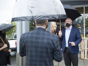 B.C. Premier John Horgan talks with Aronjit Laderi, an MRI tech at Surrey Memorial Hospital, after Horgan's campaign event at Panorama Village Shopping Centre in Surrey on Sept. 23, 2020.
