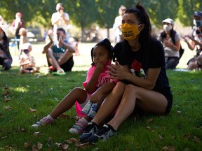 A woman and child listen to a speaker during a BLM event seeking justice and police reform in Portland.
