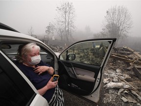 Margi Wyatt reacts after returning to find her mobile home destroyed by wildfire as her husband Marcelino Maceda (background) searches in the ruins in Estacada, Oregon Sept. 12, 2020.