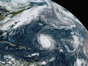 This GOES-16 GeoColor satellite image taken Friday, Sept. 18, 2020, at 12:20 p.m. EDT., and provided by NOAA, shows Hurricane Teddy, centre, in the Atlantic, Tropical Depression 22, left, in the Gulf of Mexico, the remnants Paulette, top right, and Tropical Storm Wilfred, lower right.