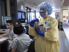 Registered nurse Cayli Hunt puts brings supplies into a COVID positive room in the COVID-19 intensive care unit at St. Paul's hospital in downtown Vancouver, Tuesday, April 21, 2020. About 250,000 employees, including front-line health care workers, will be eligible for the additional pandemic pay.