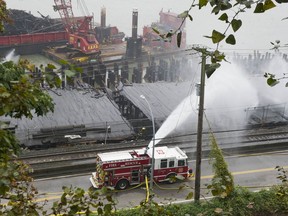 New Westminster firefighters pour water on the smouldering remains of Pier Park, destroyed earlier this week by fire.
