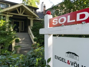 A sold sign sits on top of a for sale signs sit outside a home in Vancouver, BC, September, 6, 2020.