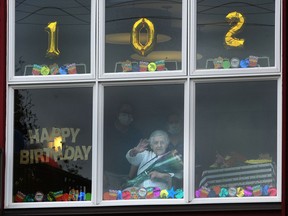 Cecilia Wikjord waves as Burnaby firefighters wish her a happy 102nd birthday with a drive-by.