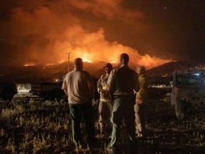 Firefighters and a police officer monitor the Brattain Fire from Withers Ranch as it burns in the Fremont National Forest in Paisley, Ore., on Sept. 18, 2020.