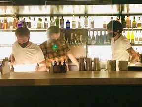Staff behind the Plexiglas at Mila's bar, located at 185 Keefer Street in Vancouver. Photo: Mia Stainsby.
