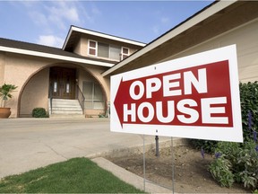 A home for sale shows the open house sign on a sunny afternoon.