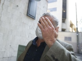 Karl Richard Antonius raises his hand to cover his face after leaving Supreme Court in Vancouver on Oct. 2, 2020.