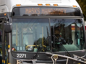 A bus driver wears a face mask to curb the spread of COVID-19 as the digital sign on the front of the bus reminds passengers that masks are mandatory on public transit.