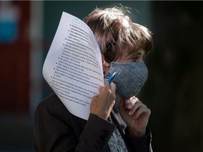 Green Party Leader Sonia Furstenau puts her face mask back on while holding her speaking notes during a campaign stop in Squamish on Sept. 29.