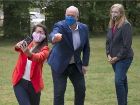 Vancouver-Langara NDP candidate Tesicca Truong takes a selfie with Premier John Horgan and Vancouver-False Creek candidate Brenda Bailey during a press conference in Vancouver on Thursday.