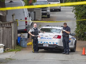 Police officers and a North Vancouver RCMP vehicle at the scene on Thursday, Oct. 1, of a double shooting the night before in an alley in the Central Lonsdale neighbourhood. Ali Reza Serri was killed and an associate wounded in the 200-block of East 17th Street.