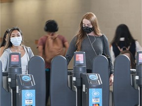 A transit users wearing masks exit the Broadway-City Hall Station in Vancouver, BC, August, 10, 2020.