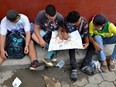 A group of Honduran migrants who are trying to reach the U.S. look at a Central America and Mexico map outside a migrant shelter as they wait to move towards the Guatemala and Mexico border, in Tecun Uman, Guatemala, on Oct. 3, 2020.