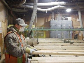 Feeding the production line, an equipment operator at C&C Wood Products checks over raw lumber flowing into the plant's machinery on its way to becoming specialty wall paneling and trim for the North American home finishing market.