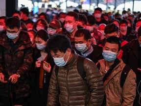 Passengers wearing face masks as a preventive measure against the Covid-19 coronavirus walk to their train at Wuhan railway station in Wuhan, China's central Hubei province on November 25, 2020.
