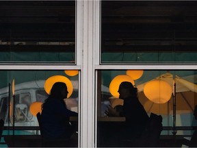 People are silhouetted while having a conversation in a restaurant on English Bay in Vancouver.