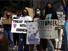 Demonstrators hold signs during a Women's March Saturday, Oct. 17, 2020, in Los Angeles. Thousands of women rallied in U.S. cities, to oppose President Donald Trump and his fellow Republican candidates in the Nov. 3 elections.