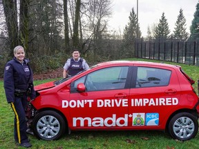 RCMP officers pose with a Mothers Against Drunk Driving (MADD) vehicle.