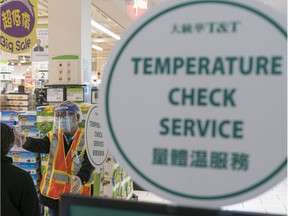 T&T Supermarket employee checks the temperature of a customer before being allowed into in Coquitlam, BC, April, 20.