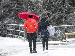 Pedestrians make their way through the snow in Surrey, December, 21, 2020.