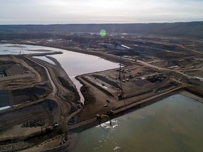 The completion of the rockfill berm officially marked the beginning of the project's river diversion phase at Site C; behind the berm, the upstream cofferdam nears full encroachment across the Peace River.