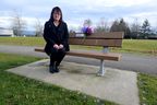 Carol Todd sitzt auf einer Gedenkbank für ihre Tochter Amanda, die nach Cybermobbing Selbstmord begangen hat.  Ein Fremder hat kürzlich an ihrem Geburtstag die Bank mit Amandas lila Lieblingsblumen geschmückt.