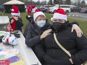 British Columbian Melanie Robertson (in black mask) visits with her mom Jayne Johnson (blue mask) from Blaine, at Peace Arch Historical State Park on Friday as friends and family from either side of the Canada-U.S. border visited on Christmas Day.
