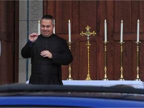 Father James Hughes, (l) with a lectern set up outside the church doors in Vancouver, BC., on December 24, 2020.