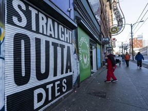 A man uses an ATM at the Bank of Montreal in Chinatown while homeless men are in the lobby.