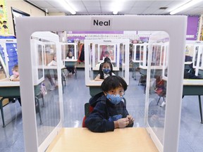 Ontario school children wearing masks sit behind screened cubicles at St. Barnabas Catholic School in Scarborough, Ont. Schools in B.C. don't seem to be on the same page with masks and other protocols, which has increased anxiety and frustration with parents and educators.