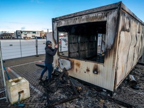 A man takes a photograph of a torched drive-in coronavirus test centre in the port Urk, on Jan. 24, 2021, after youth went on the rampage protesting the first night of a curfew in the Netherlands since the occupation during Second World War.
