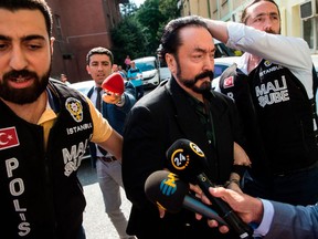 Turkish police officers escort televangelist and leader of a sect, Adnan Oktar (C) on July 11, 2018, in Istanbul, as he is detained on fraud charges. Turkish police detained the televangelist on fraud charges on July 11, 2018, notorious for propagating conservative views while surrounded by scantily-clad women he refers to as his "kittens".