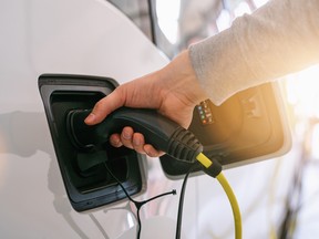 Hand holding Electric car charger. Power supply electric car charging for electric car technology transportation in the future.