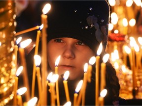 A girl lights a candle during a church service.