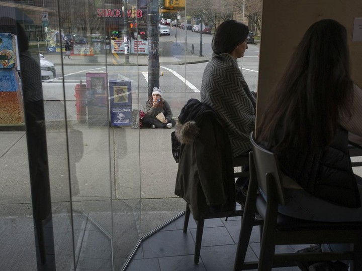  A panhandler sits outside the JJ Bean Coffee Roasters location at East 14th and Main Street in Vancouver.