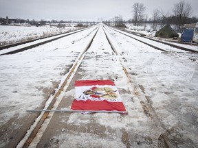 A Canadian maple leaf flag with native symbols on it lays on the train tracks in Tyendinaga Mohawk Territory, near Belleville, Ont., on Tuesday, Feb. 11, 2020. Members of the Mohawk territory blocked the CN/VIA tracks in support of Wet'suwet'en's blockade of natural gas pipeline in northern B.C.