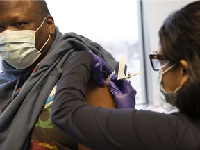 Dr. Stephaun Wallace, who leads the global external relations strategies COVID-19 Prevention Network at the Fred Hutchinson Cancer Research Center, receives his second injection from Dr. Tia Babu during the Novavax COVID-19 vaccine Phase 3 clinical trial at the UW Virology Research Clinic on Feb. 12 in Seattle.