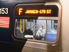 A woman with a face mask rides on the subway in Brooklyn.