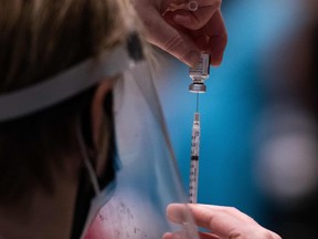 A nurse practitioner loads a syringe with the Pfizer COVID-19 vaccine.