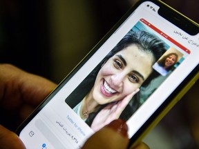 This picture taken February 10, 2021 in Saudi Arabia's capital Riyadh shows a woman viewing a tweet posted by the sister of Saudi activist Loujain al-Hathloul, Lina, showing a screenshot of them having a video call following Hathloul's release after nearly three years in detention.