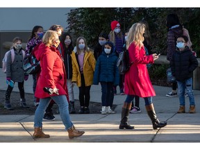 Students watch as teachers dressed in red participate in a solidarity march to raise awareness about cases of COVID-19 at Ecole Woodward Hill Elementary School in Surrey on Tuesday.
