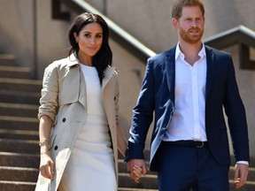 In this file photo taken on October 16, 2018 Britain's Prince Harry and his wife Meghan walk down the stairs of Sydneys iconic Opera House.