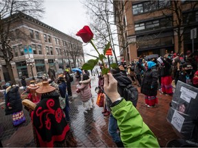 A person holds up a single red rose during the annual Women's Memorial March in Vancouver, B.C., Sunday, Feb. 14, 2021.
